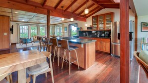 Una cocina espaciosa con una isla grande, armarios de madera y un techo alto con vigas a la vista.