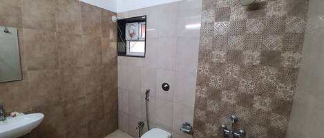 Un baño con inodoro, lavabo, ducha y toallero.