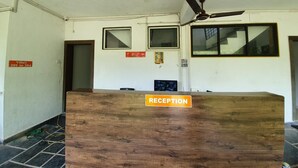 Un mostrador de recepción con un cartel que dice 'RECEPTION' en un edificio con varias ventanas y un ventilador de techo.