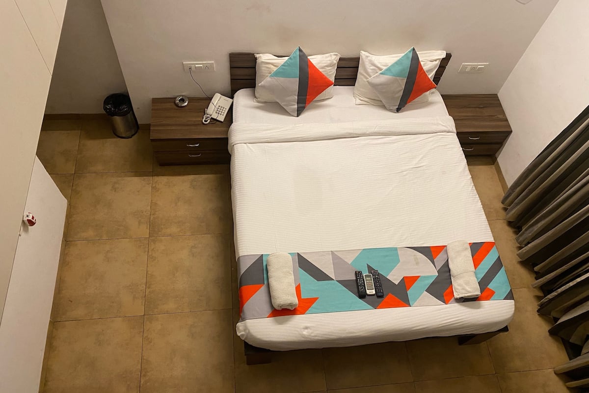 A hotel room with a bed, a nightstand, a phone, and a radiator.