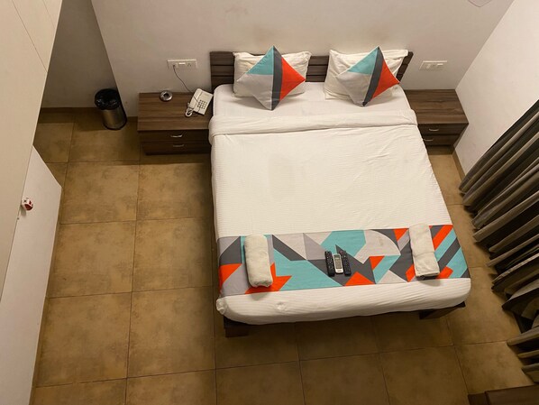 A hotel room with a bed, a nightstand, a phone, and a radiator.
