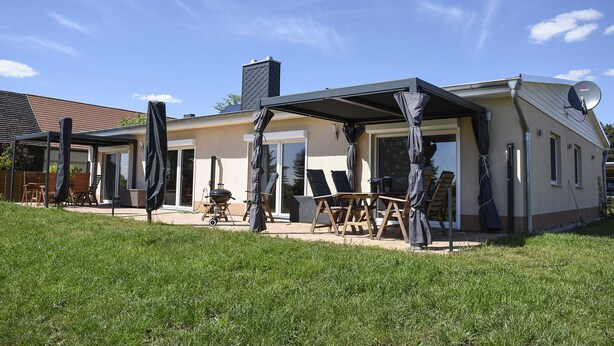 A modern house with a covered patio, outdoor seating, and a satellite dish. - Barrier-free apartment 14b (Trüben)