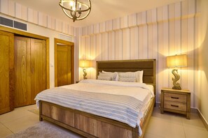 A bedroom with a wooden bed, two bedside tables with lamps, a wooden wardrobe, and a ceiling light fixture. - Marvelous Ocean Views, Harmony 6FLR Apt at Las Olas Metro Country Club - Unit #2 (Playa Juan Dolio)