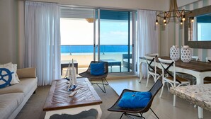 Habitación de hotel con balcón, zona de comedor y área de estar con vista al océano.