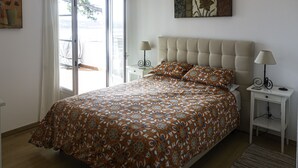 A bedroom with a large bed, two bedside tables, a window with curtains, and a painting on the wall.