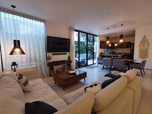 Relax in this stylish living room with a plush sofa, flat-screen TV, and dining area.