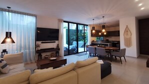 Un salon moderne avec un canapé, un téléviseur et un coin repas.