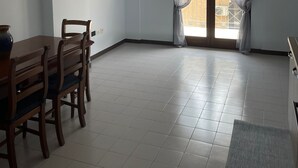 A room with a dining table and chairs, a large window with sheer curtains, and a tiled floor. - Bluemar Guest House (Castellammare di Stabia)