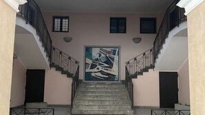 A staircase with a large abstract painting at the top, flanked by two black railings and a beige wall. - Bluemar Guest House (Castellammare di Stabia)