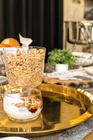 Una bandeja con un vaso de yogur cubierto de granola y otro vaso de yogur cubierto de granola y fruta roja.