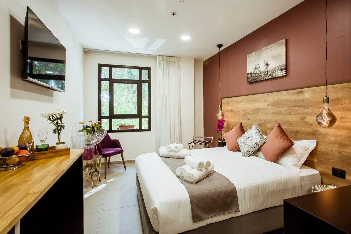A hotel room with a bed, a desk, a chair, a TV, and a window.