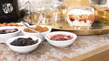 Una variedad de postres en una bandeja, incluyendo recipientes con diferentes tipos de compota y un vaso de parfait de yogur.