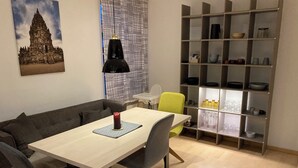 Un espace repas comprenant une table, des chaises, une bibliothèque et un mur orné d’un motif décoratif.