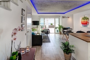 A modern living room with a sofa, a dining table with candles, and a view to the outside.