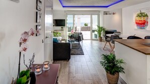 A modern living room with a dining area, a kitchen, and a balcony with a view.