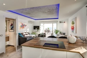 A modern kitchen with a wooden countertop, a built-in oven, and a blue ceiling light.