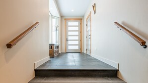 Una escalera con escalones de piedra oscura que conduce a una puerta con un panel de vidrio esmerilado.