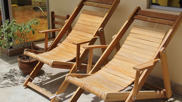 Two wooden lounge chairs with metal frames, positioned on a concrete floor with a potted plant nearby. - Casa de Ana Huaraz (Independencia)