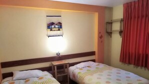 A hotel room with two single beds, a small table, a wall-mounted shelf, and a window with a curtain. - Casa de Ana Huaraz (Independencia)