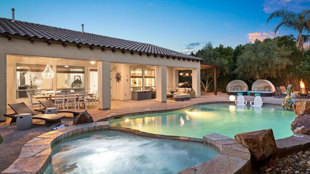 Une maison moderne dotée d’une piscine, d’un espace salon extérieur et d’un patio.