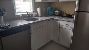 Een keuken met witte kasten, een roestvrijstalen koelkast, een spoelbak en een broodrooster.