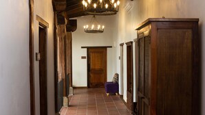 Un couloir avec des poutres en bois, un lustre et un banc violet.