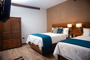 Une chambre d’hôtel avec deux lits, des têtes de lit en bois et une armoire.