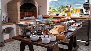 Un buffet de petit-déjeuner avec un four à briques, une variété de plats et une vue sur les montagnes.