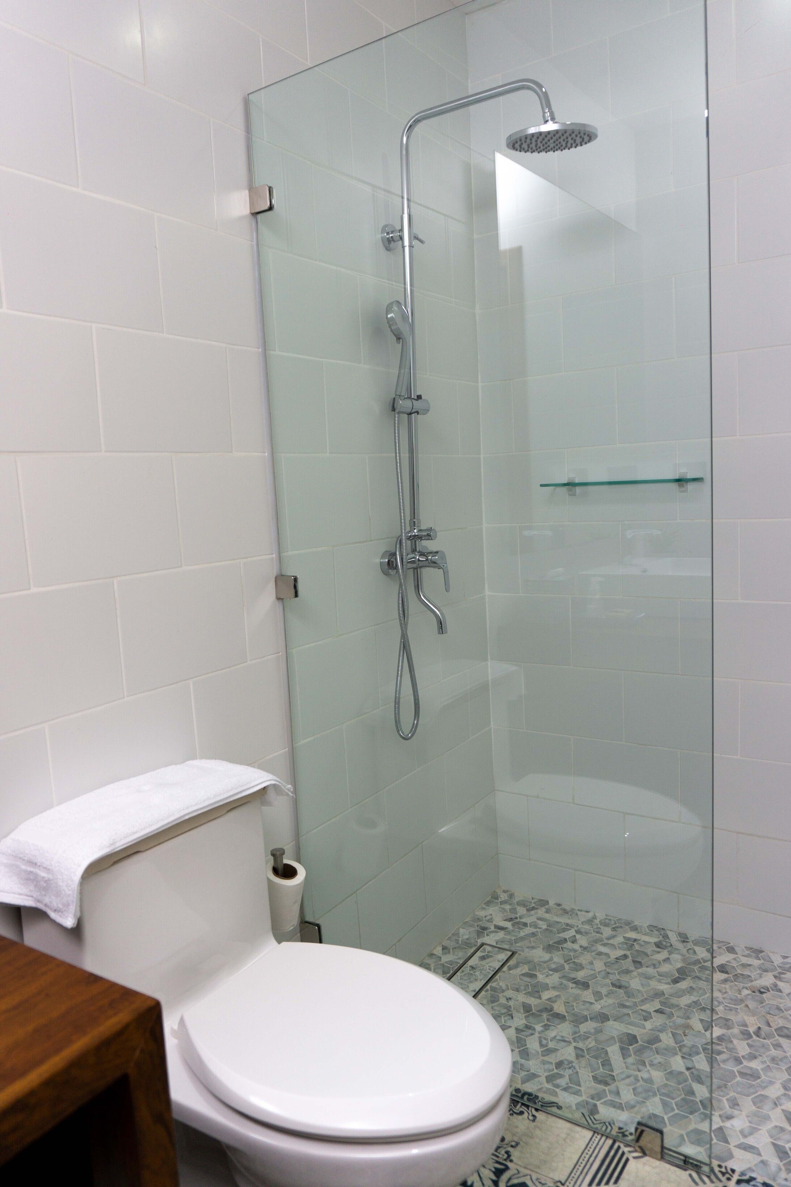 Ein Badezimmer mit Duschkabine, Toilette und einem gemusterten Boden.