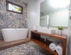 Une salle de bain avec une baignoire sur pieds, un lavabo avec un miroir et un meuble-lavabo en bois.