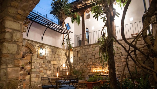Une cour dallée avec une table et des chaises, entourée de plantes et d’une pergola.