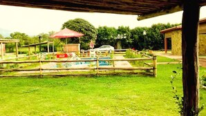 An outdoor area with a pool, a wooden fence, and a covered seating area. - Cabañas Villa del Sol (Rosario de Lerma)