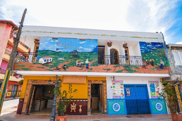 A building with a mural depicting a rural scene, a blue gate, and a sign for a pet store.