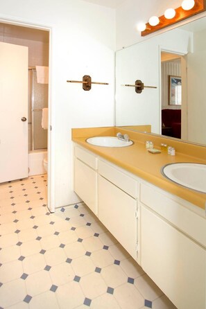 Une salle de bain avec deux lavabos, un miroir avec éclairage int égré et une douche.