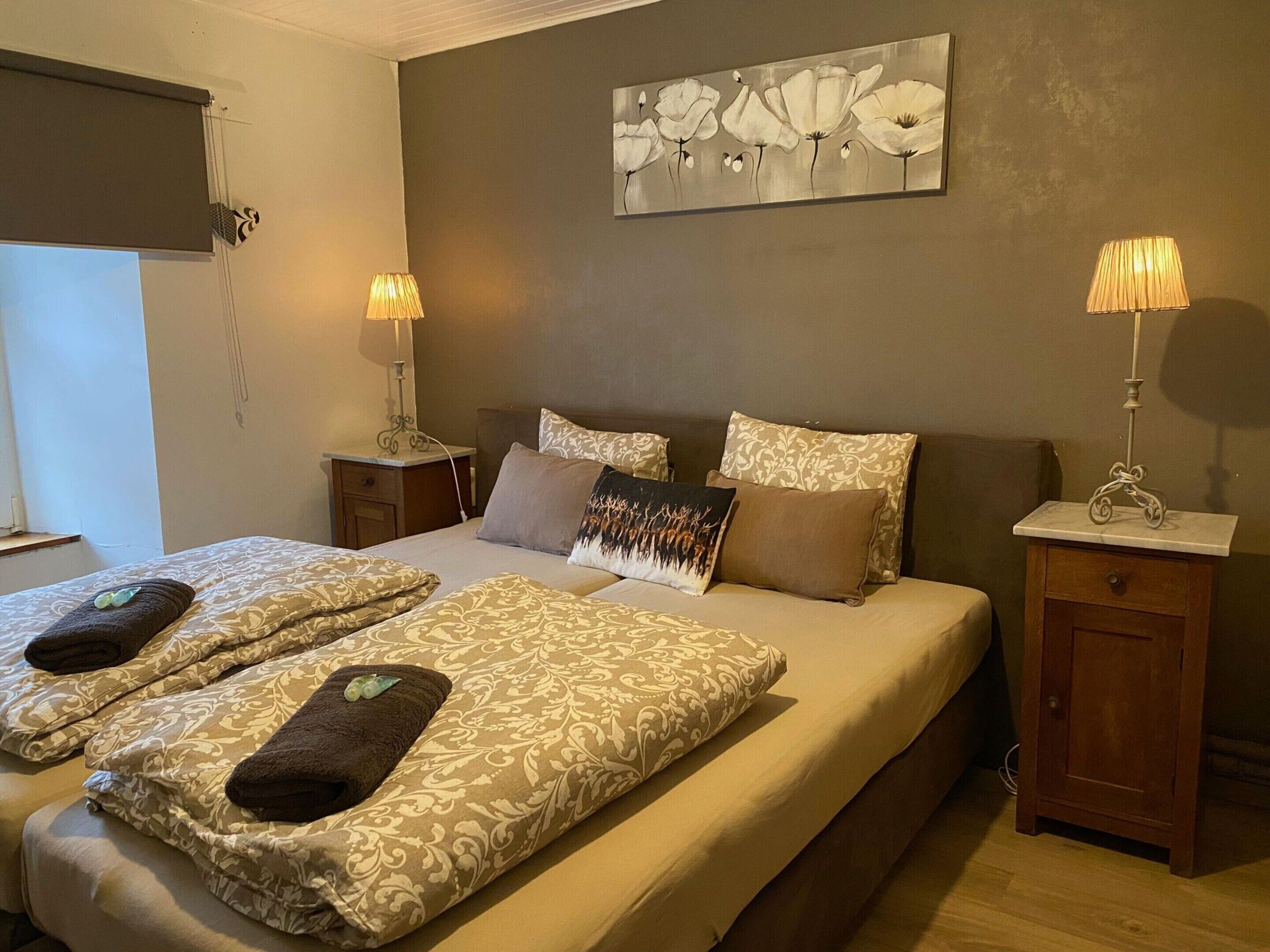 A double bed with patterned bedding and two bedside tables with lamps.