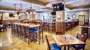 Un restaurante amplio con varias mesas y sillas, una zona de bar y un televisor en la pared.