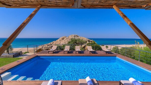 A swimming pool with lounge chairs and a view of the sea.
