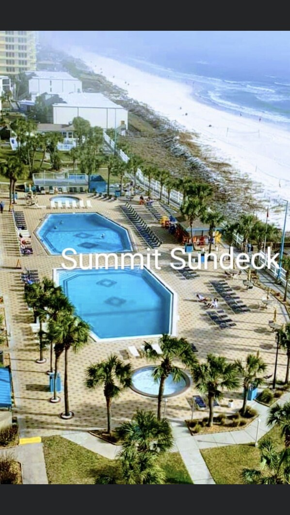 A resort with a large swimming pool, smaller pools, and a beach area.