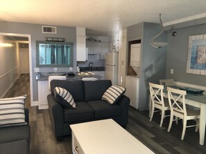A compact living space with a kitchenette, a dining area, and a sofa with striped pillows.