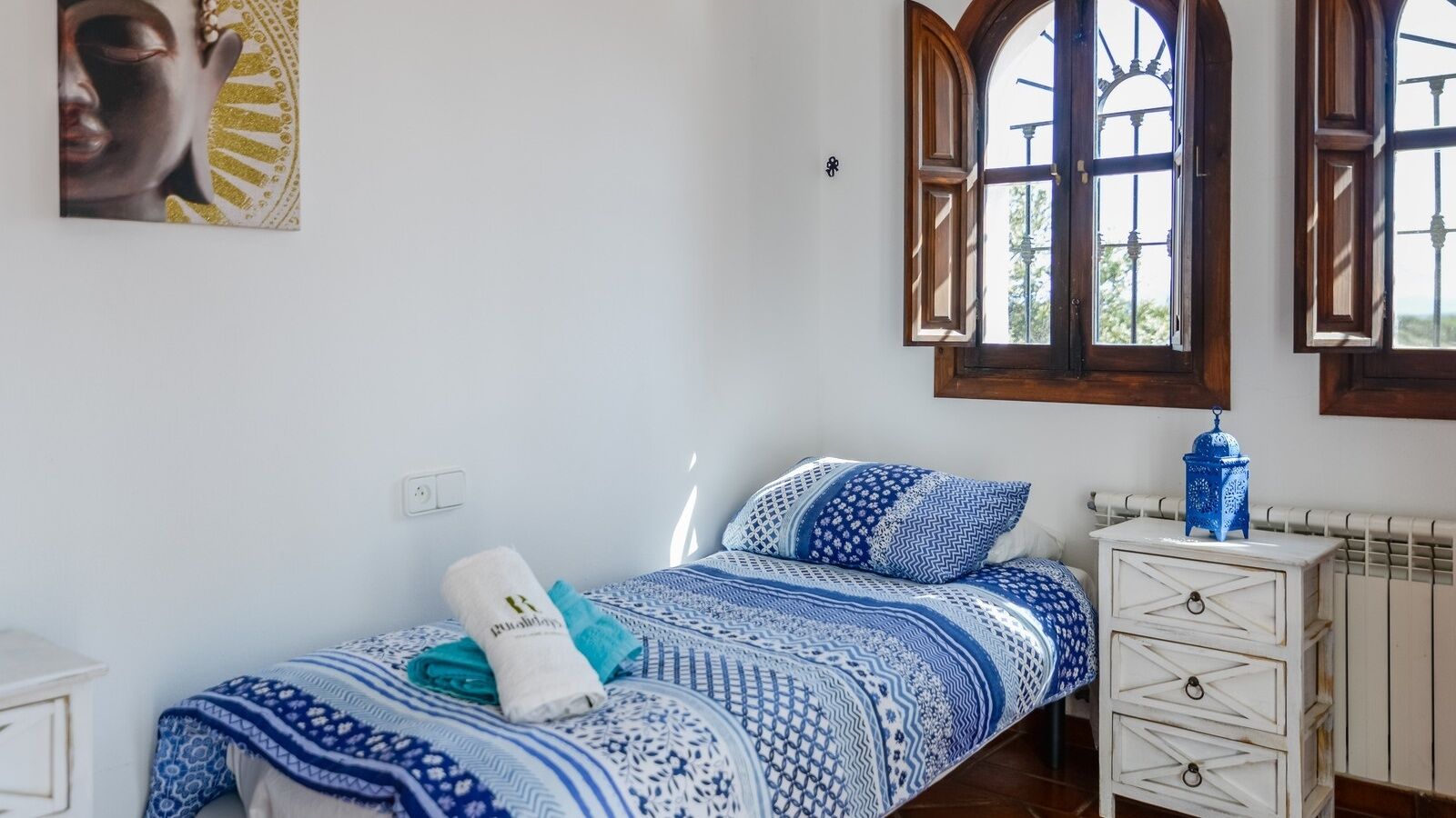 Une chambre à coucher comprenant un lit, une table de chevet, une fenêtre et un interrupteur fixé au mur.