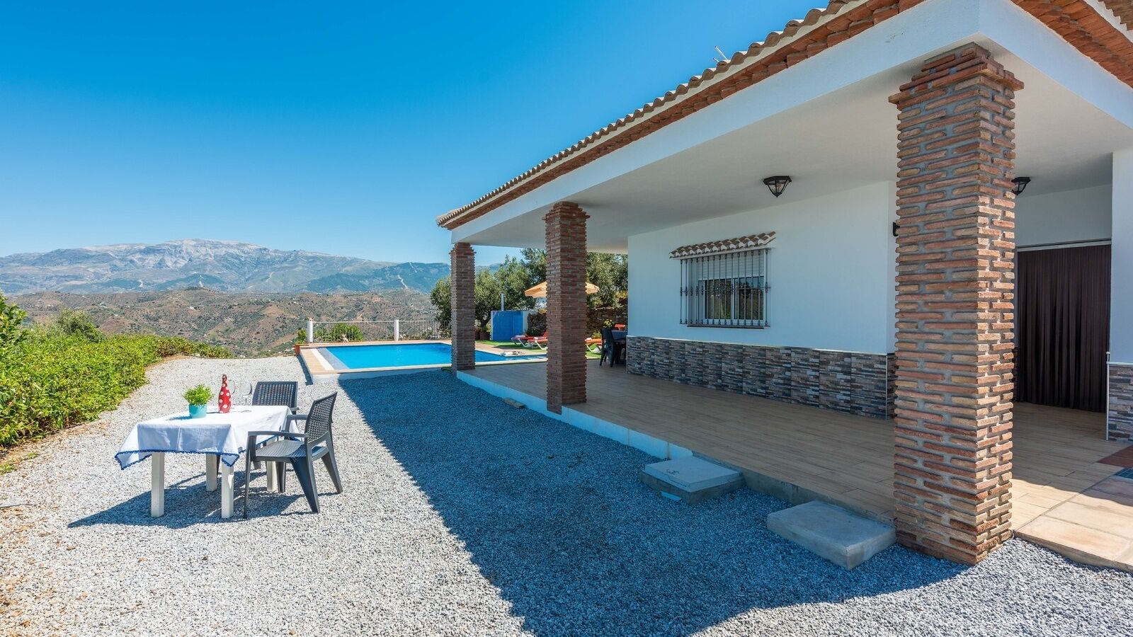 A house with a pool, outdoor seating, and a view of mountains.
