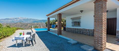 A house with a pool, outdoor seating, and a view of mountains.