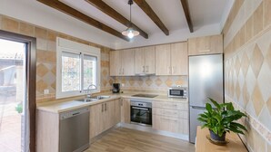 A modern kitchen with wooden cabinets, a built-in oven, a microwave, and a dishwasher. - Villa Dajabe Sayalonga by Ruralidays (Málaga)