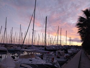 A marina with numerous boats docked, a calm water surface, and a sunset sky.