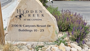 Un grand panneau en pierre portant l’inscription : « Hidden Creek, au cœur des canyons, 2100 W Canyons Resort Dr, bâtiments 10 à 23 ».