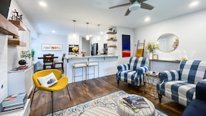 Una sala de estar moderna con un sofá, sillones, una mesa de centro y una zona de comedor con barra.