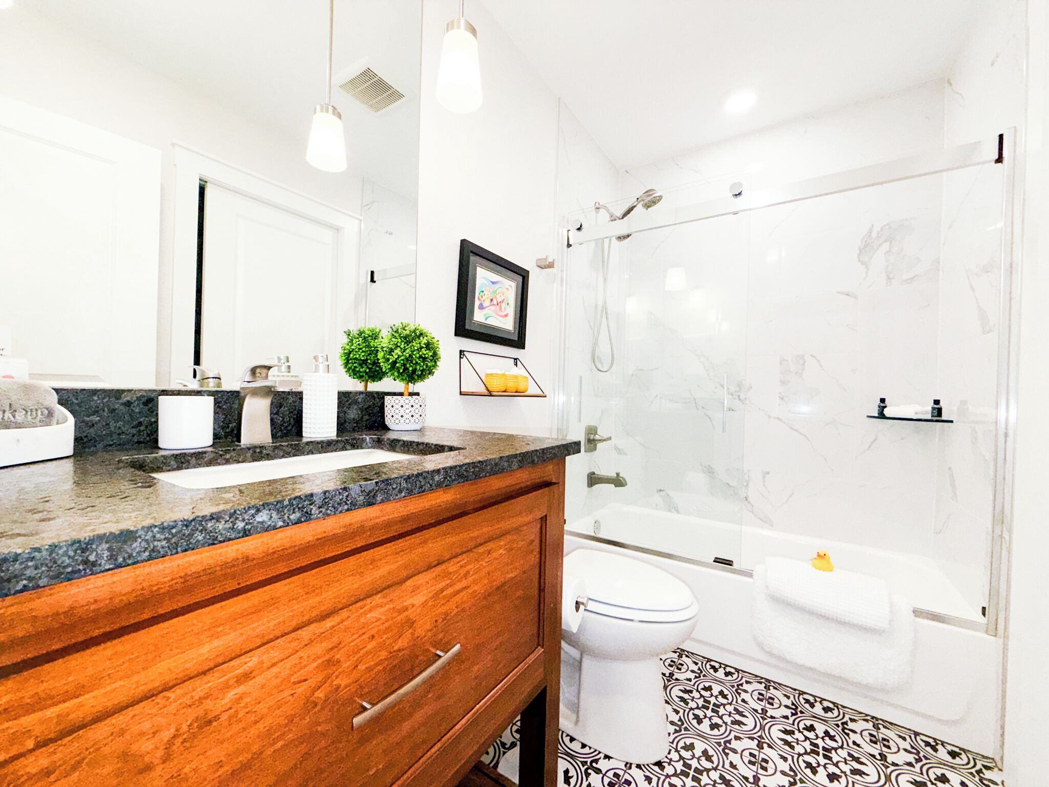 Une salle de bain moderne avec une douche en marbre, des toilettes blanches et un meuble-lavabo en bois avec un évier.