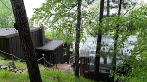 Une cabane dotée d’une terrasse, entourée d’une forêt dense.