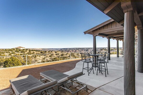 A terrace with lounge chairs and tables, offering a view of a desert landscape.