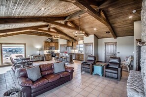 A spacious living area with a leather sofa, a dining table, and a kitchen in the background.
